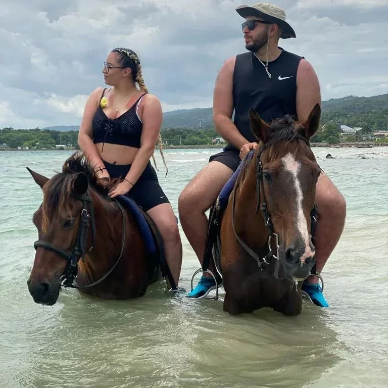 Guests horseback riding in shallow water with Romaine Tours Jamaica