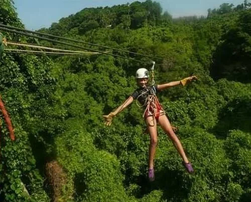 Guest on a zipline above green Jamaican hills